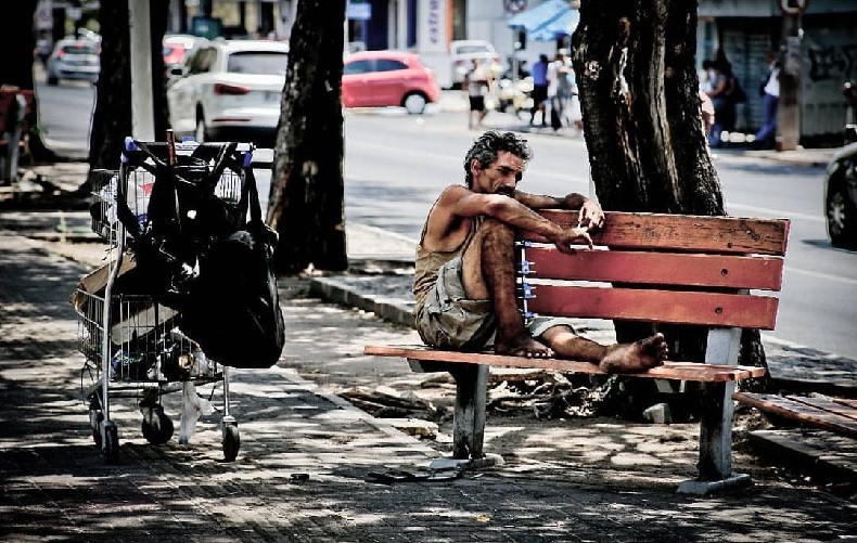 Morador de rua sentado em banco no canteiro da Avenida Frei Serafim